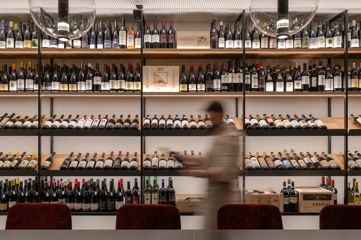 Interno dell'Enoteca da Aldo a Bolzano con scaffalatura di bottiglie illuminate